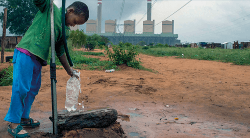 Kind am Wasserbrunnen vor dem Kohlekraftwerk Kusile, Südafrika 