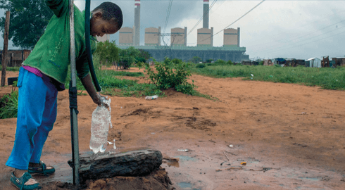 Kind am Wasserbrunnen vor dem Kohlekraftwerk Kusile, Südafrika
